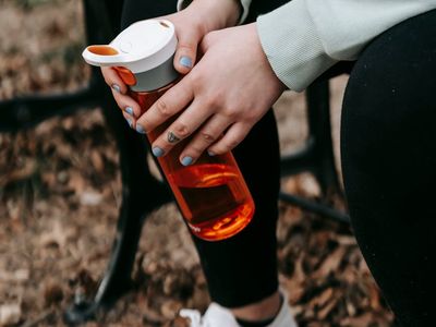 Sneakers and a water bottle on a wooden bench.